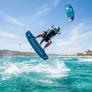 A kitesurfer performing a high action jump over turquoise water